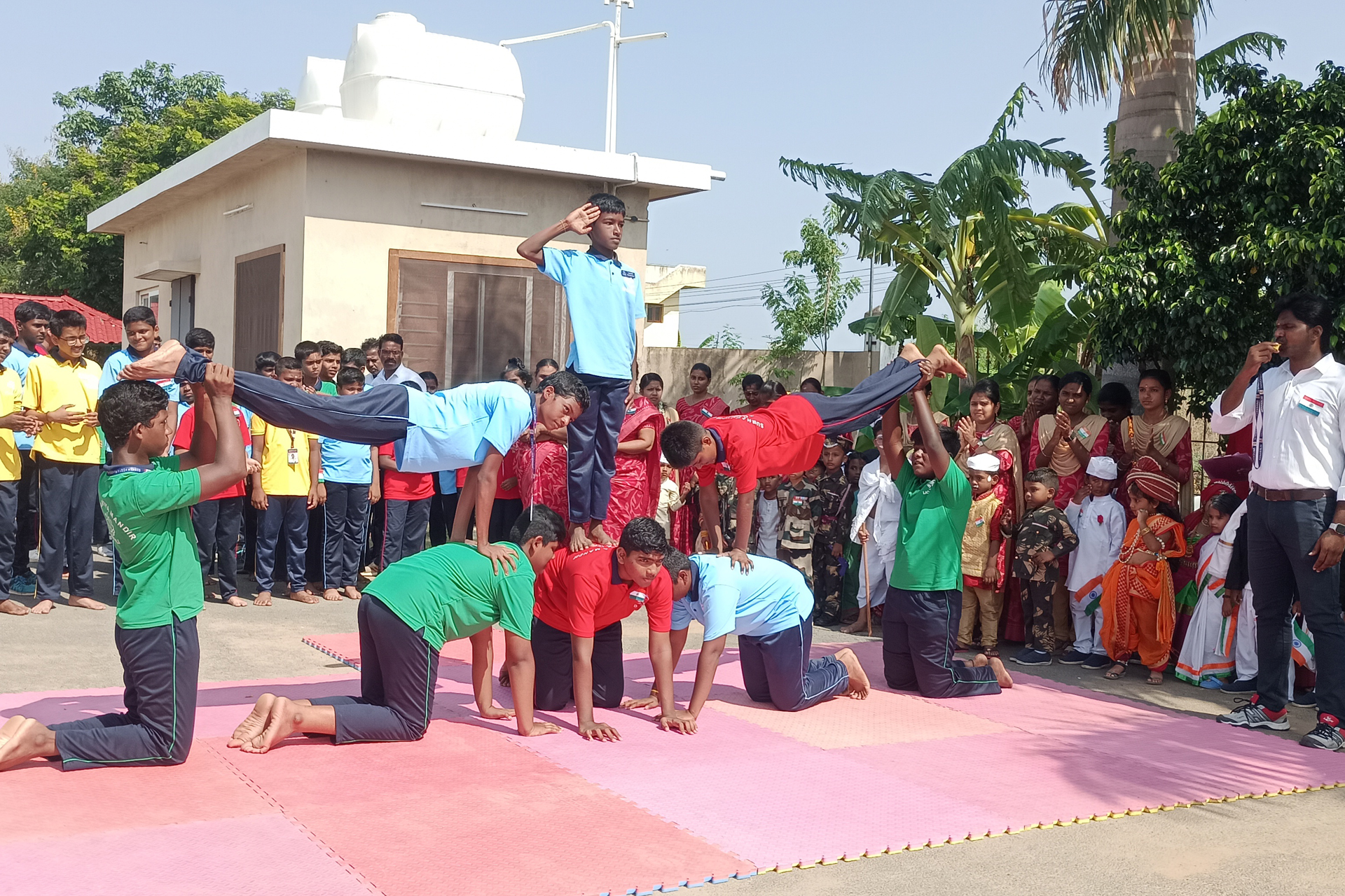 A set of students are watching three of their classmates involved in performing arts at the stage.